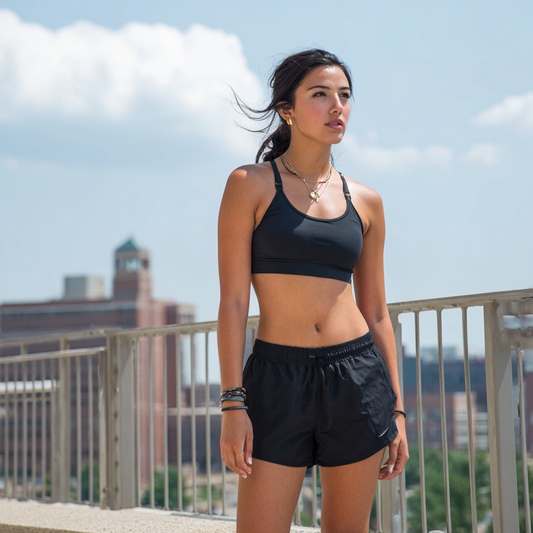 Women's Athletic Shorts – Swift Performance Shorts Woman in athletic wear standing on a balcony with a cityscape background